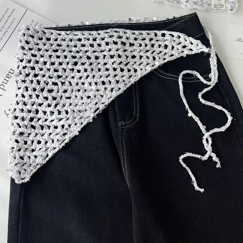 Weißes Dreieckstuch mit offenem Netzmuster und Bindebändern, auf einer schwarzen Jeans ausgelegt