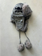 Graue Camouflage-Uschanka mit Totenkopfmotiv, flauschigen Ohrenklappen und Bommeln an langen Bändern