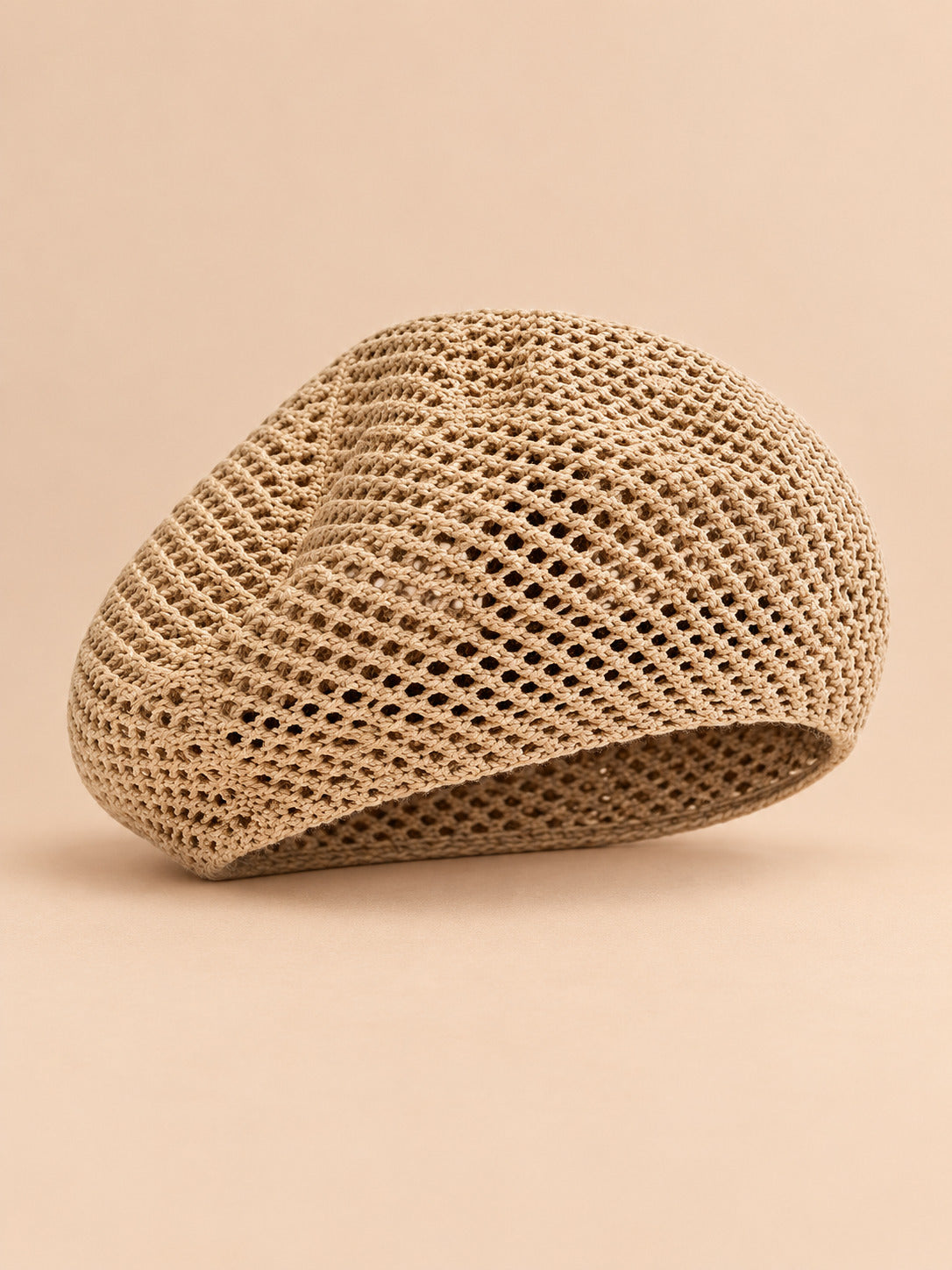 Béret d’artiste ajouré kaki, vue de face sur fond pêche sable