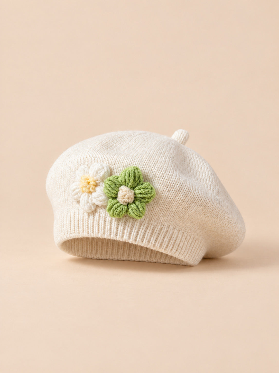 Béret bébé fille Beige à fleurs en relief au crochet, vue de face sur fond pêche sable