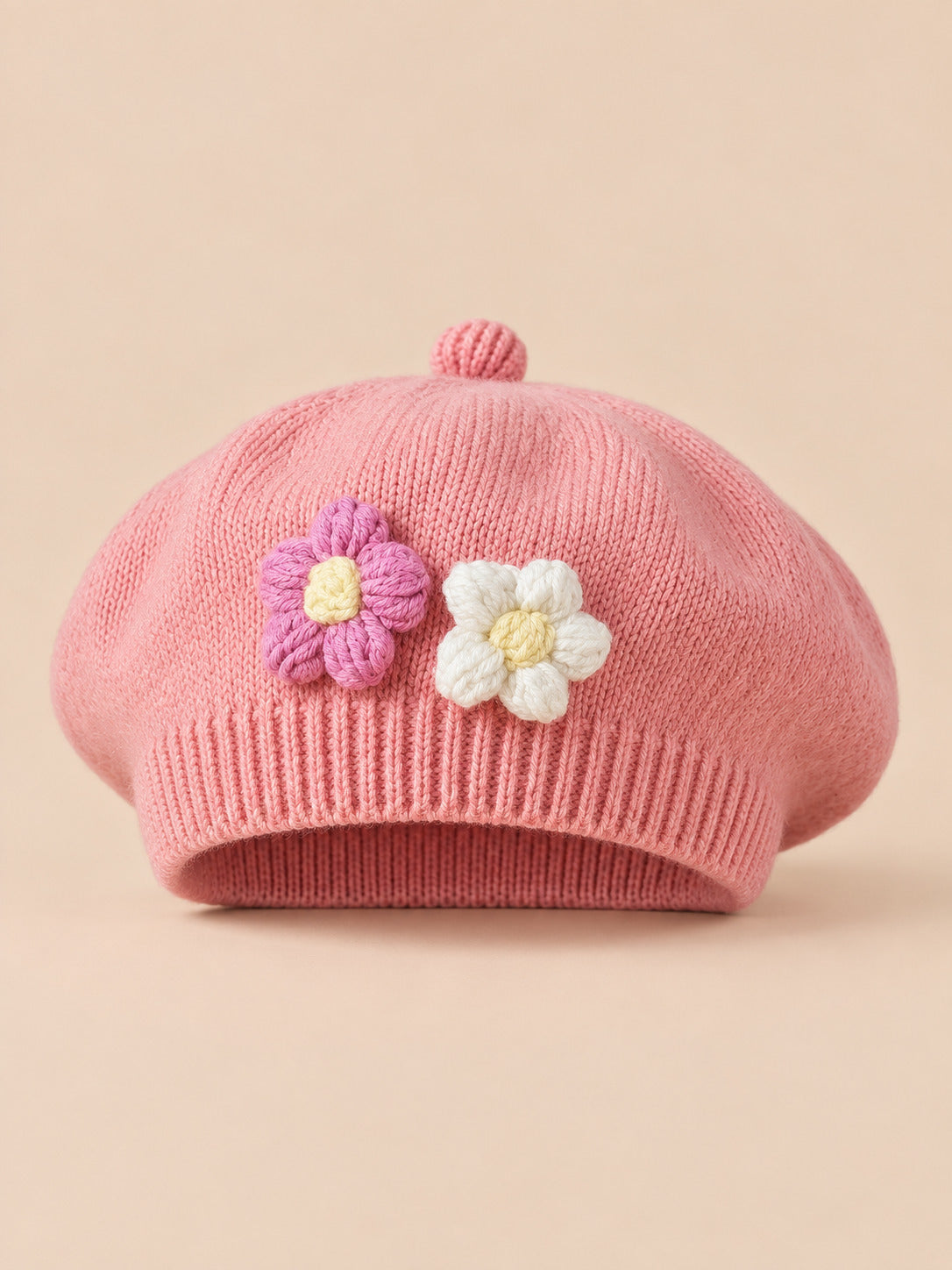 Béret bébé fille Rose nude à fleurs en relief au crochet, vue de face sur fond pêche sable