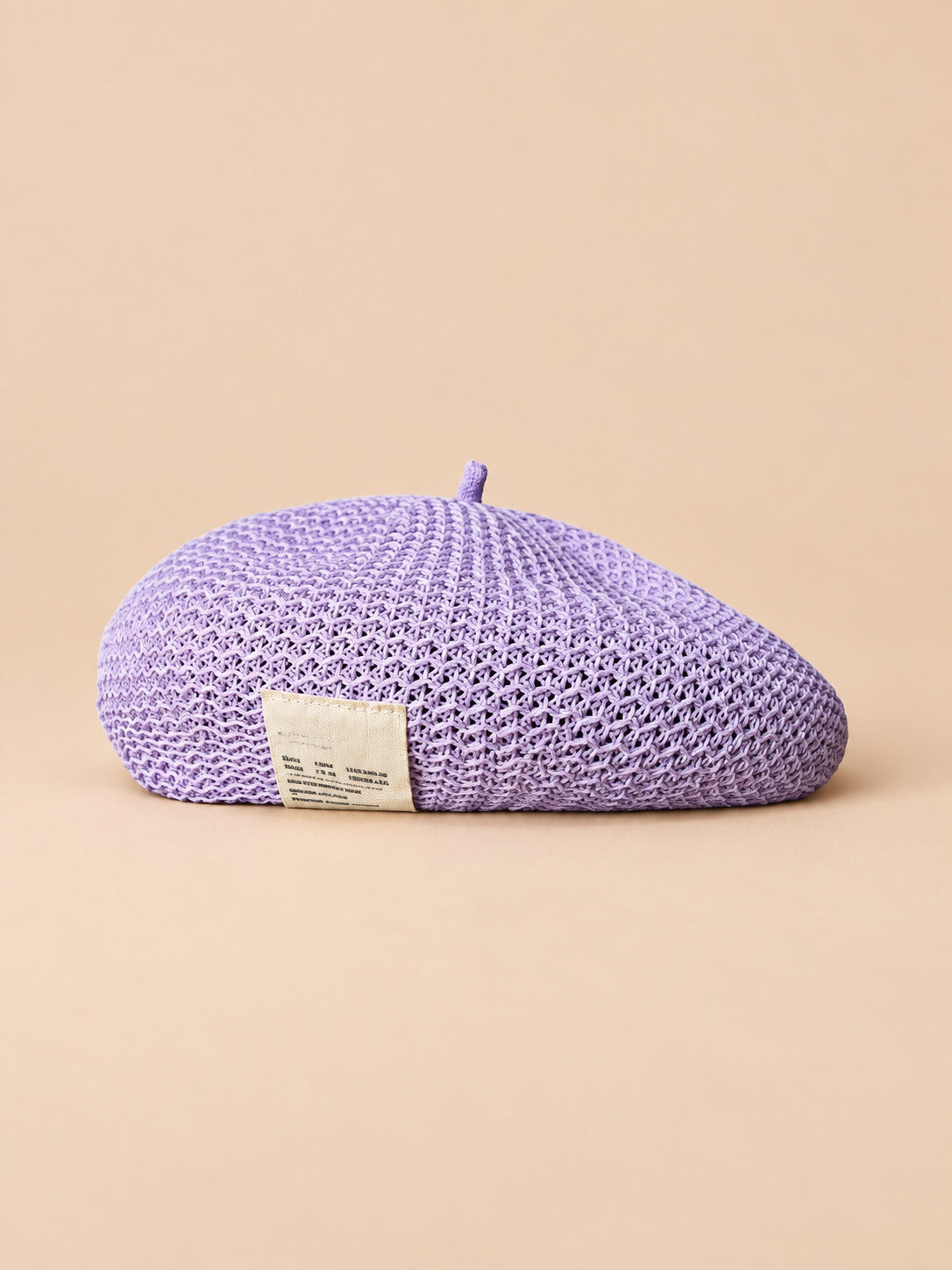 Béret d’été en lin ajouré lavande, vue de face sur fond pêche sable