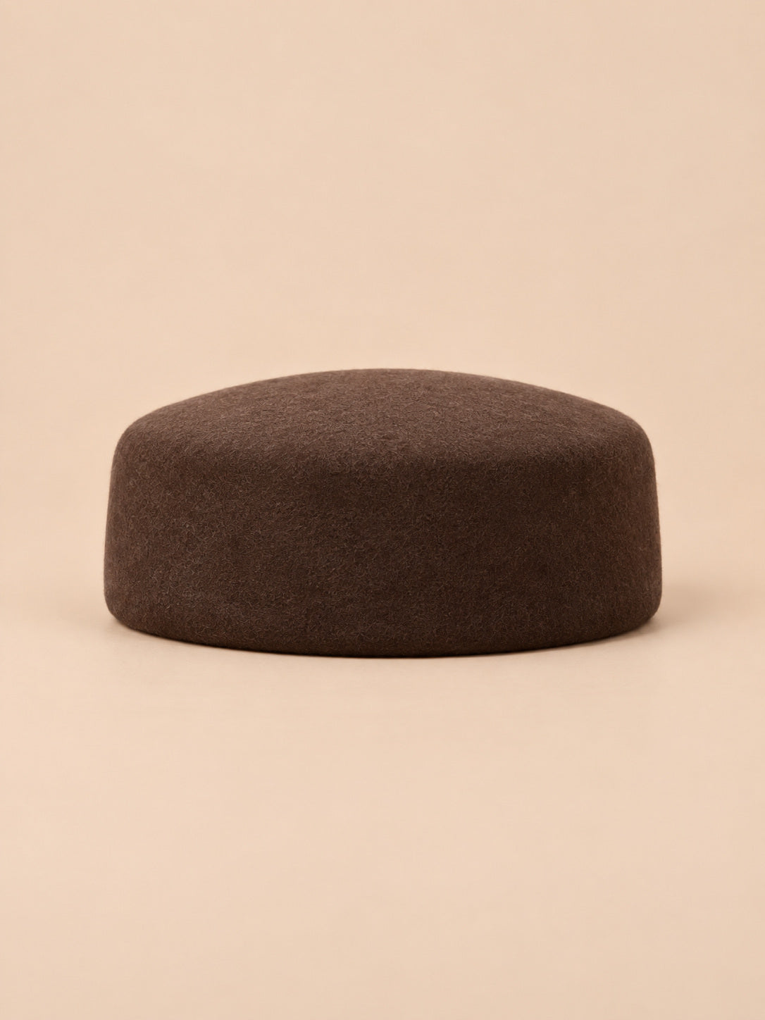 Béret femme en laine feutrée café, forme plat, vue de face sur fond pêche sable
