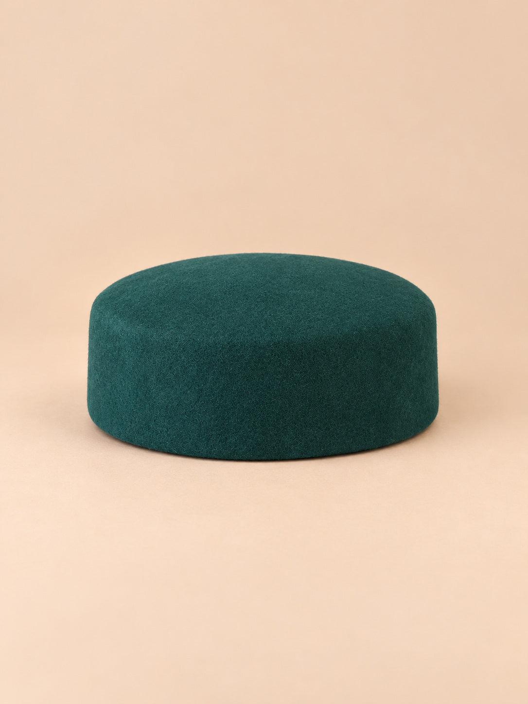 Béret femme en laine feutrée vert foncé, forme plat, vue de face sur fond pêche sable