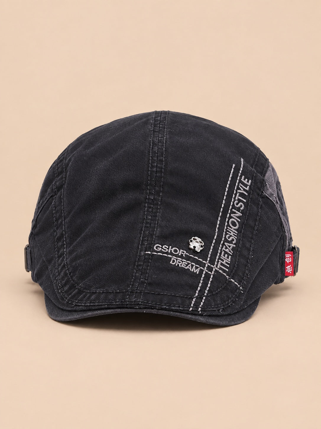 Béret gavroche en coton noir, vue de face sur fond pêche sable