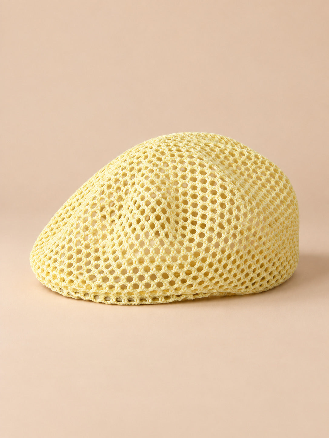 Béret résille ajouré jaune, vue de face sur fond pêche sable