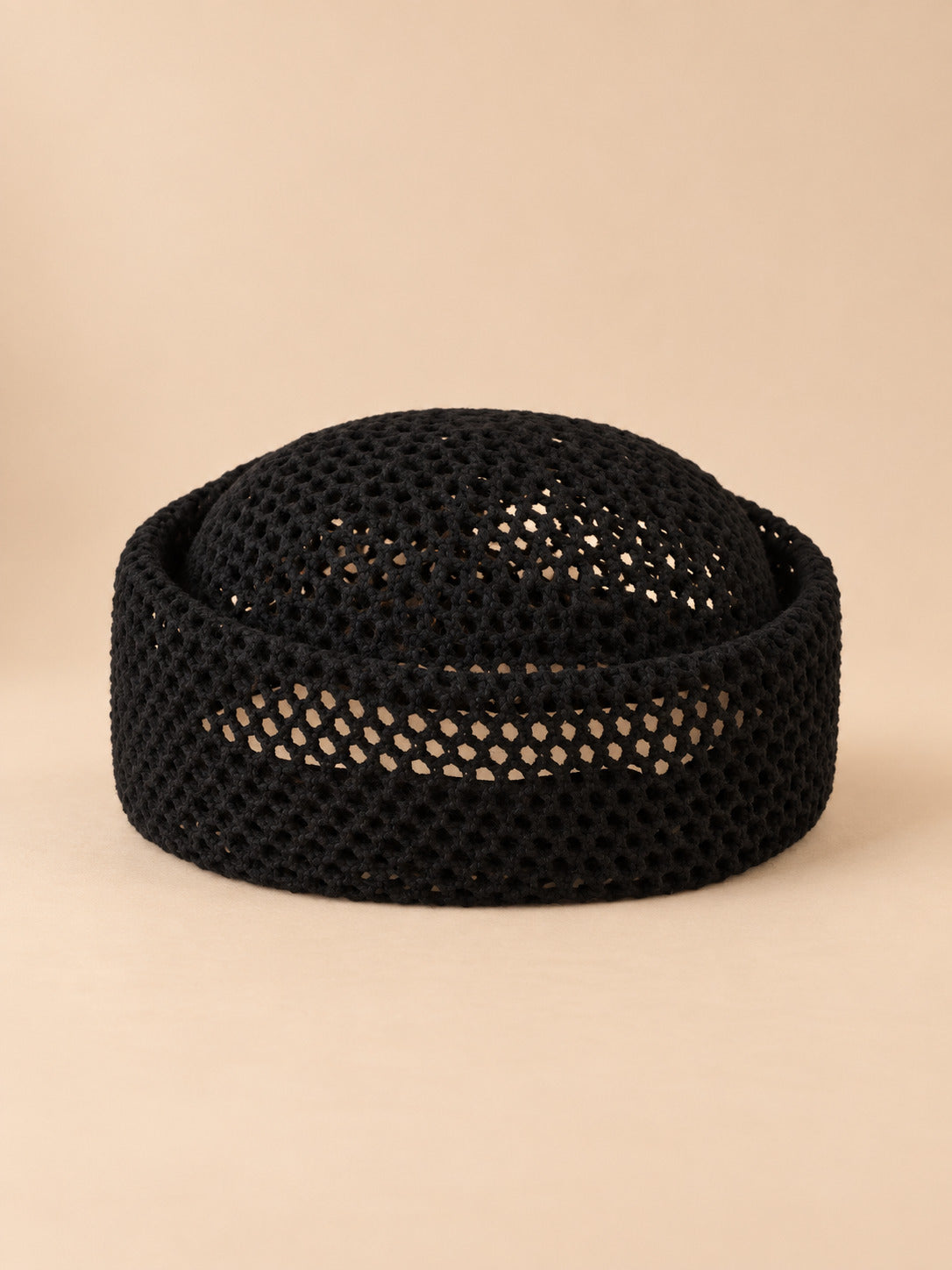 Béret résille ajouré noir 1, vue de face sur fond pêche sable