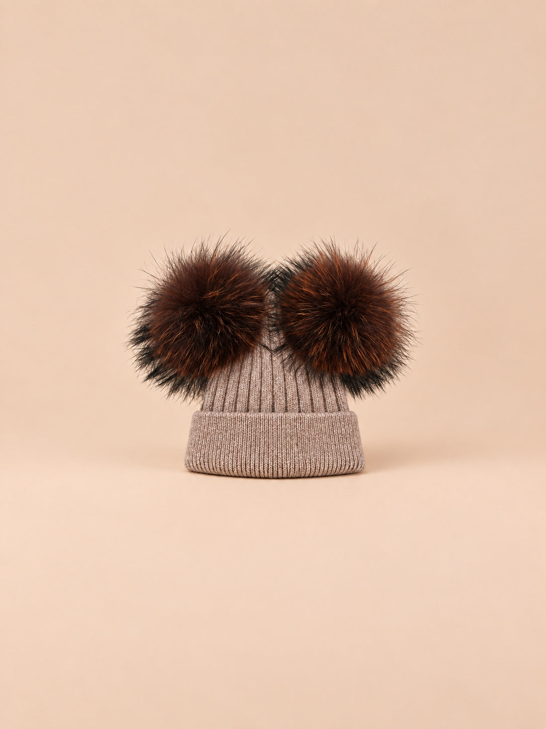 Bonnet double pompon, marron, pompons assortis, vue de face sur fond pêche sable.