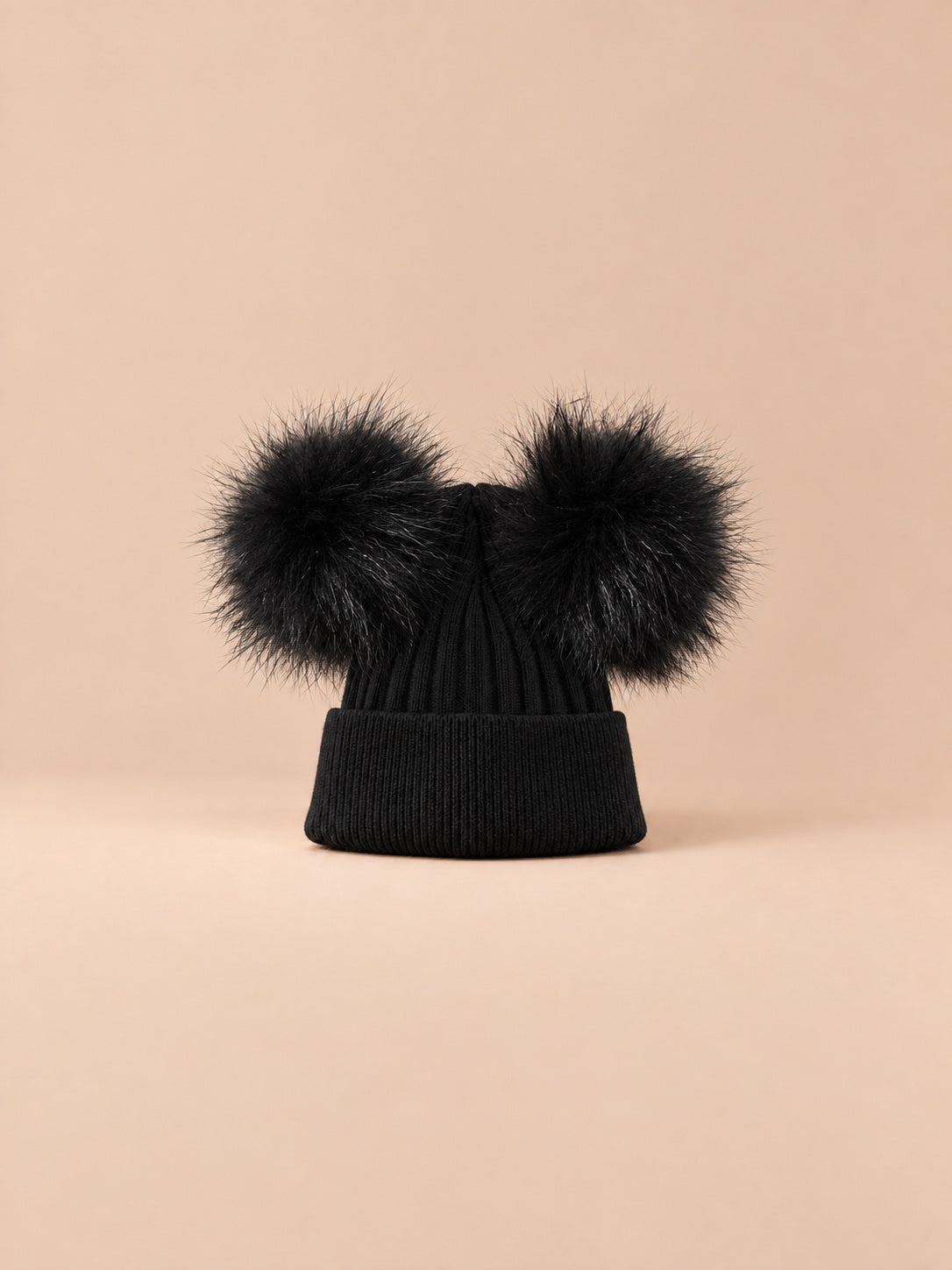 Bonnet double pompon, noir, pompons assortis, vue de face sur fond pêche sable.