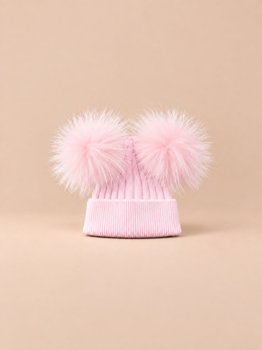Bonnet double pompon, rose, pompons assortis, vue de face sur fond pêche sable.