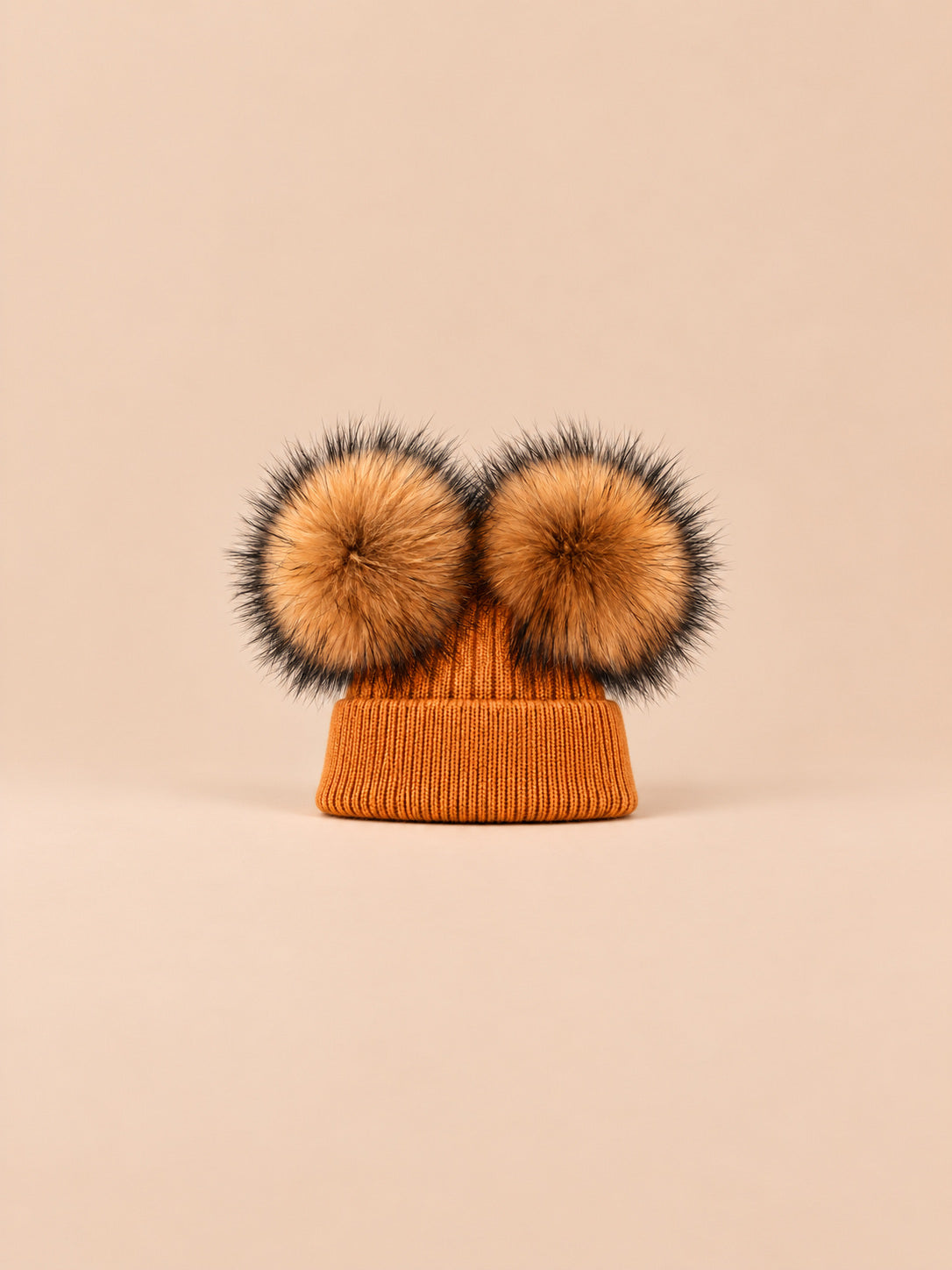 Bonnet double pompon, roux, pompons naturels, vue de face sur fond pêche sable.