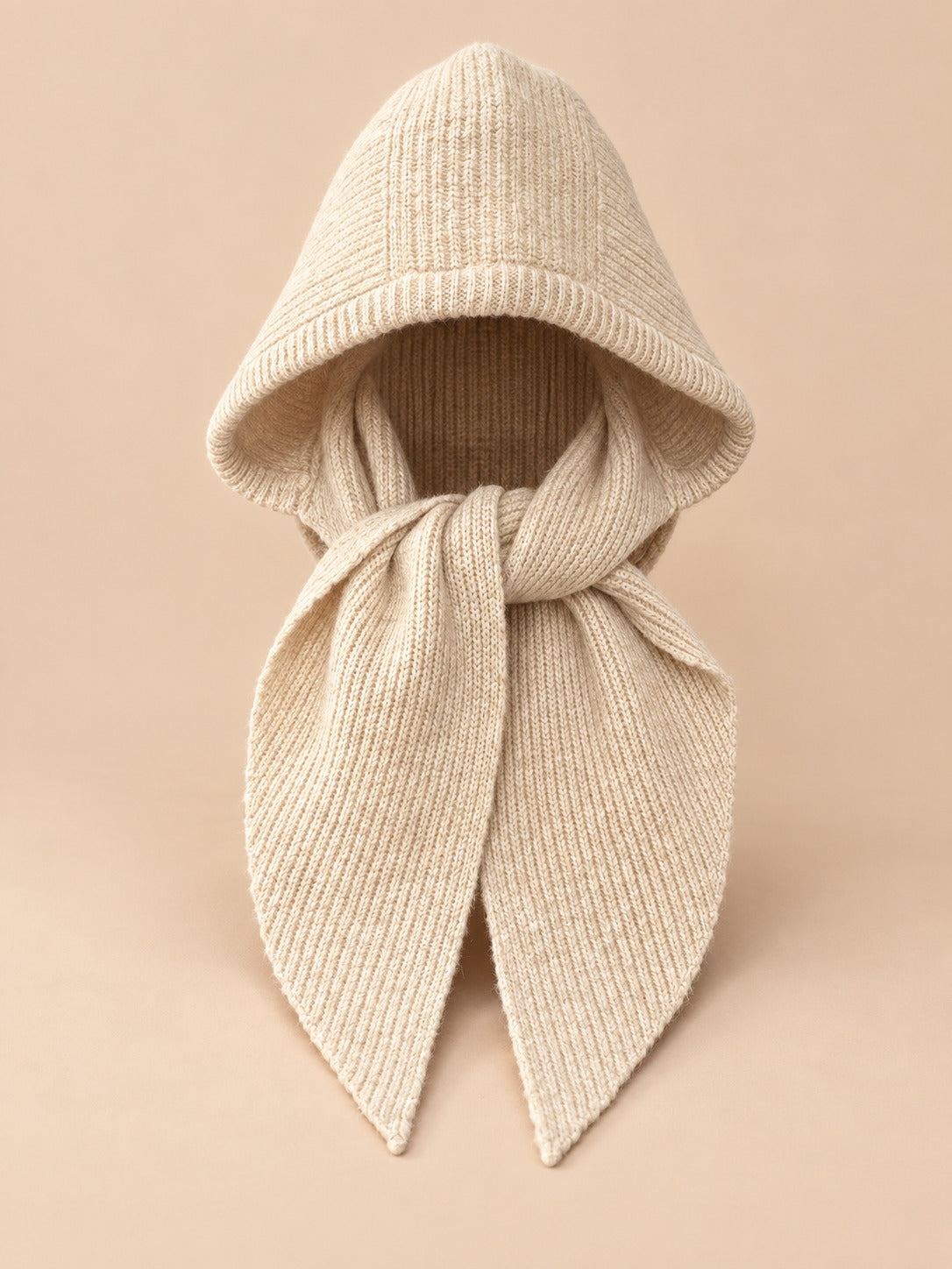 Cagoule bonnet-écharpe beige en maille, vue de face sur fond pêche sable