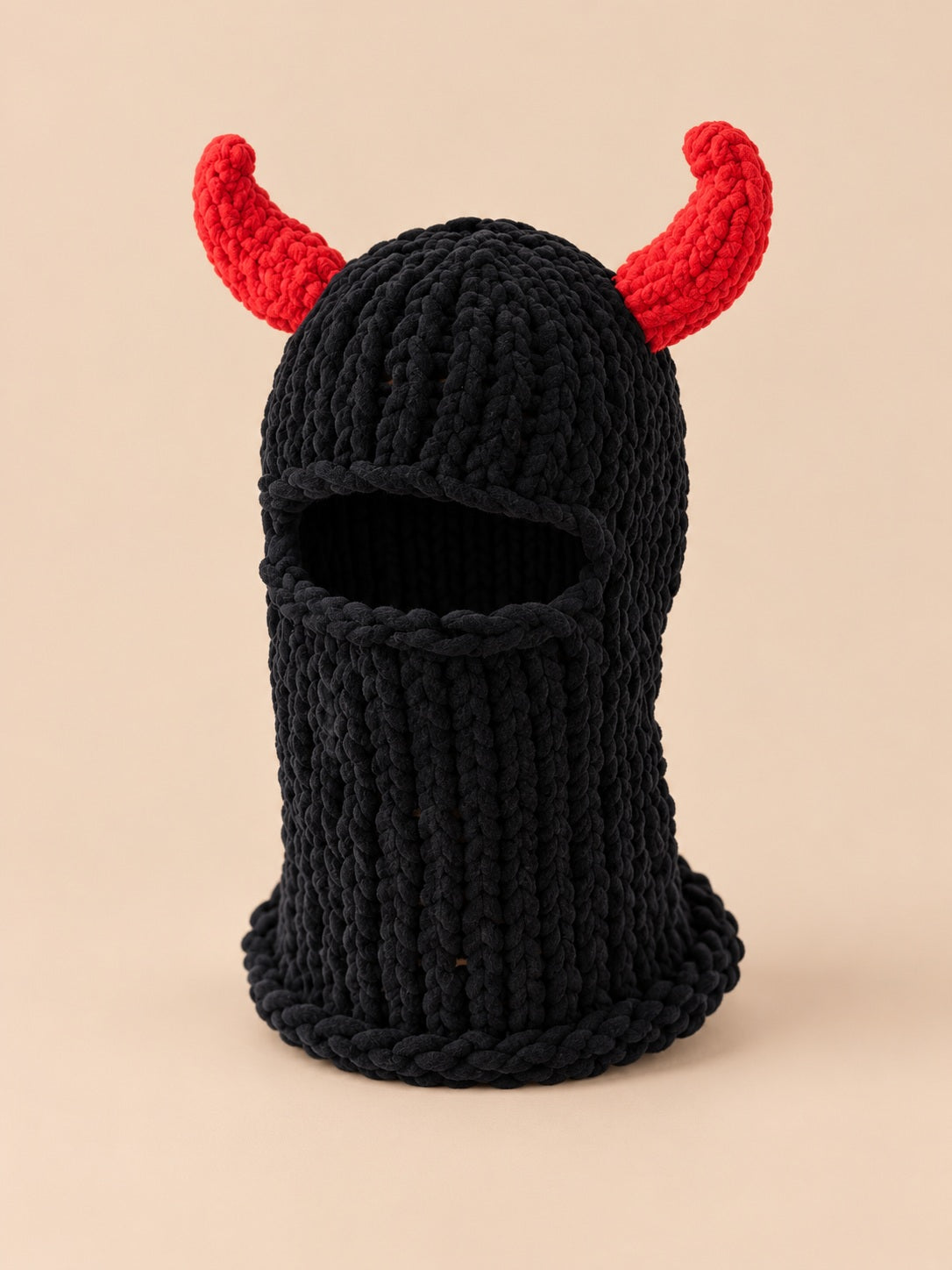 Cagoule crochet cornes de diable modèle 1 noire et rouge, vue de face sur fond pêche sable