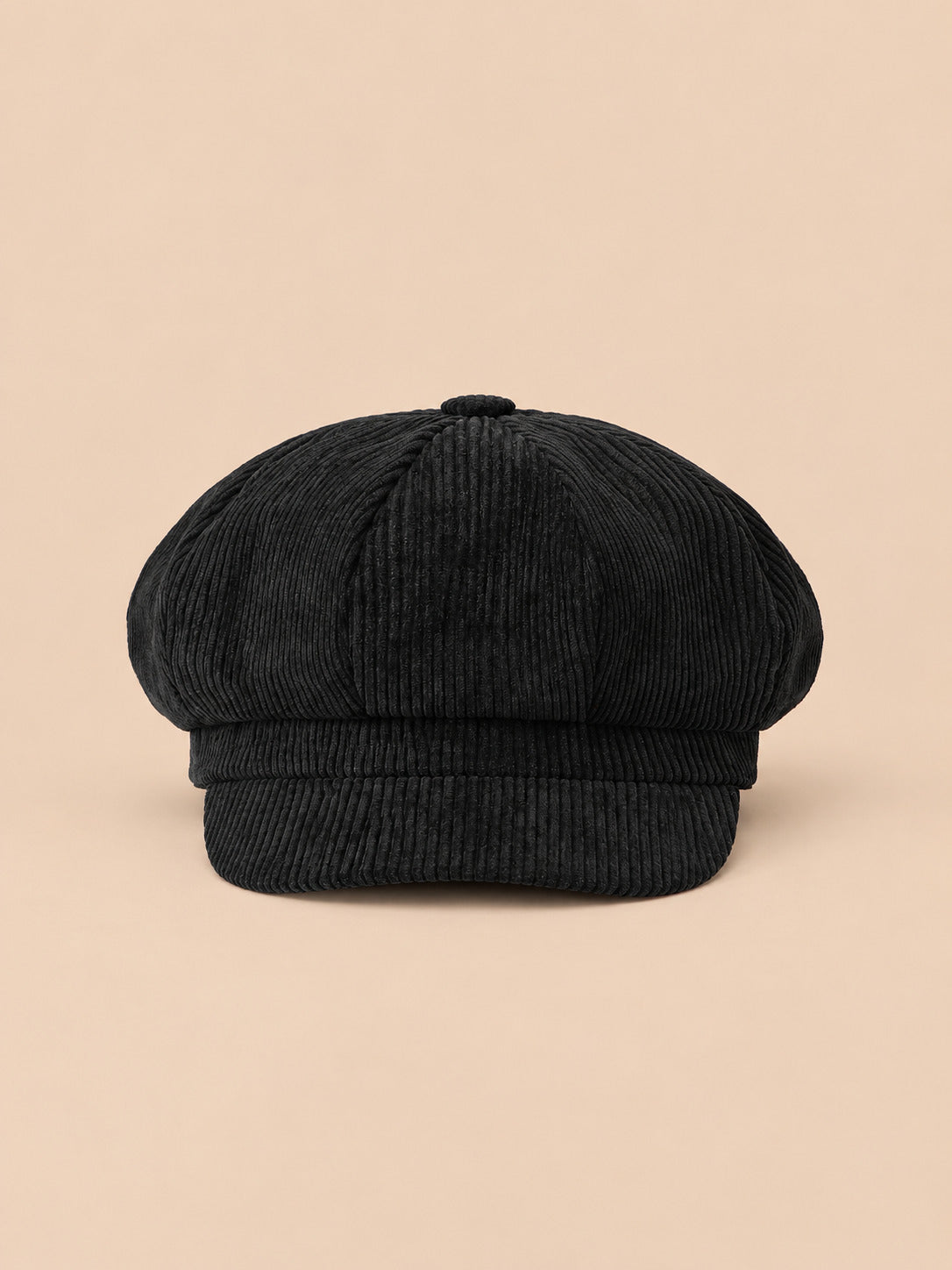 Casquette gavroche octogonale en velours côtelé noir, vue de face sur fond pêche sable