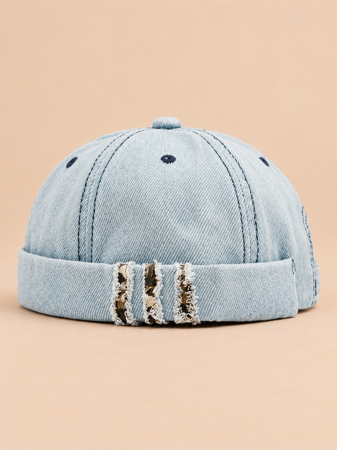 Bonnet docker en denim bleu clair, revers effiloché à détails léopard, vue de face.