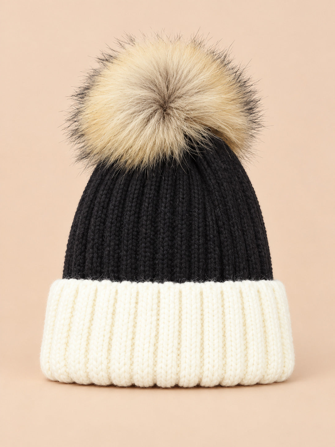 Bonnet enfant à pompon noir 2, vue de face sur fond pêche sable