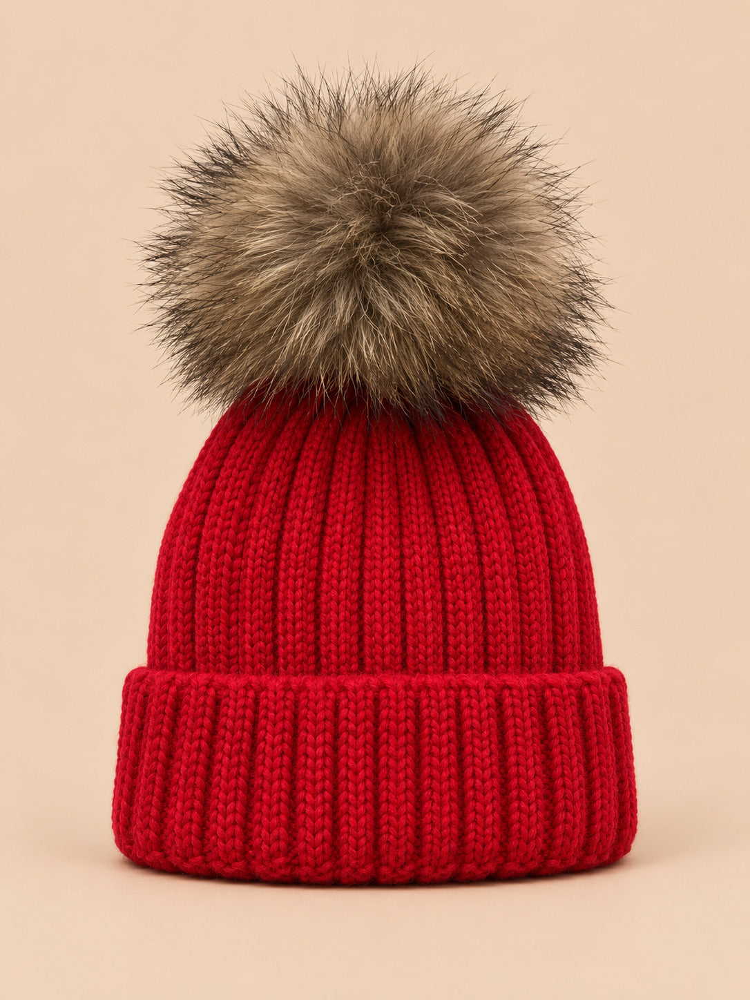 Bonnet enfant à pompon rouge, vue de face sur fond pêche sable