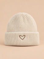 Mütze aus dem Mütze-Schal-Set für Kinder – Farbvariante Beige, Ansicht von vorn, sand-pfirsichfarbener Hintergrund