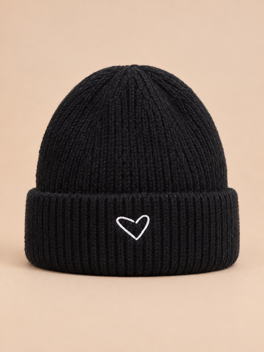 Bonnet enfant noir en maille, vue de face, fond pêche sable