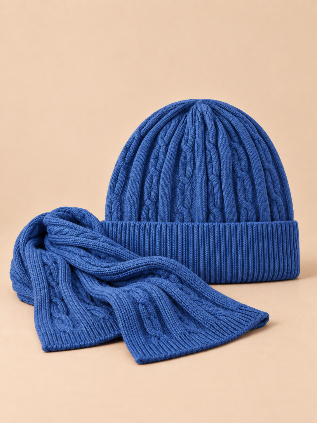 Ensemble bonnet à revers et écharpe en laine jacquard bleue, vue de face sur fond pêche sable.