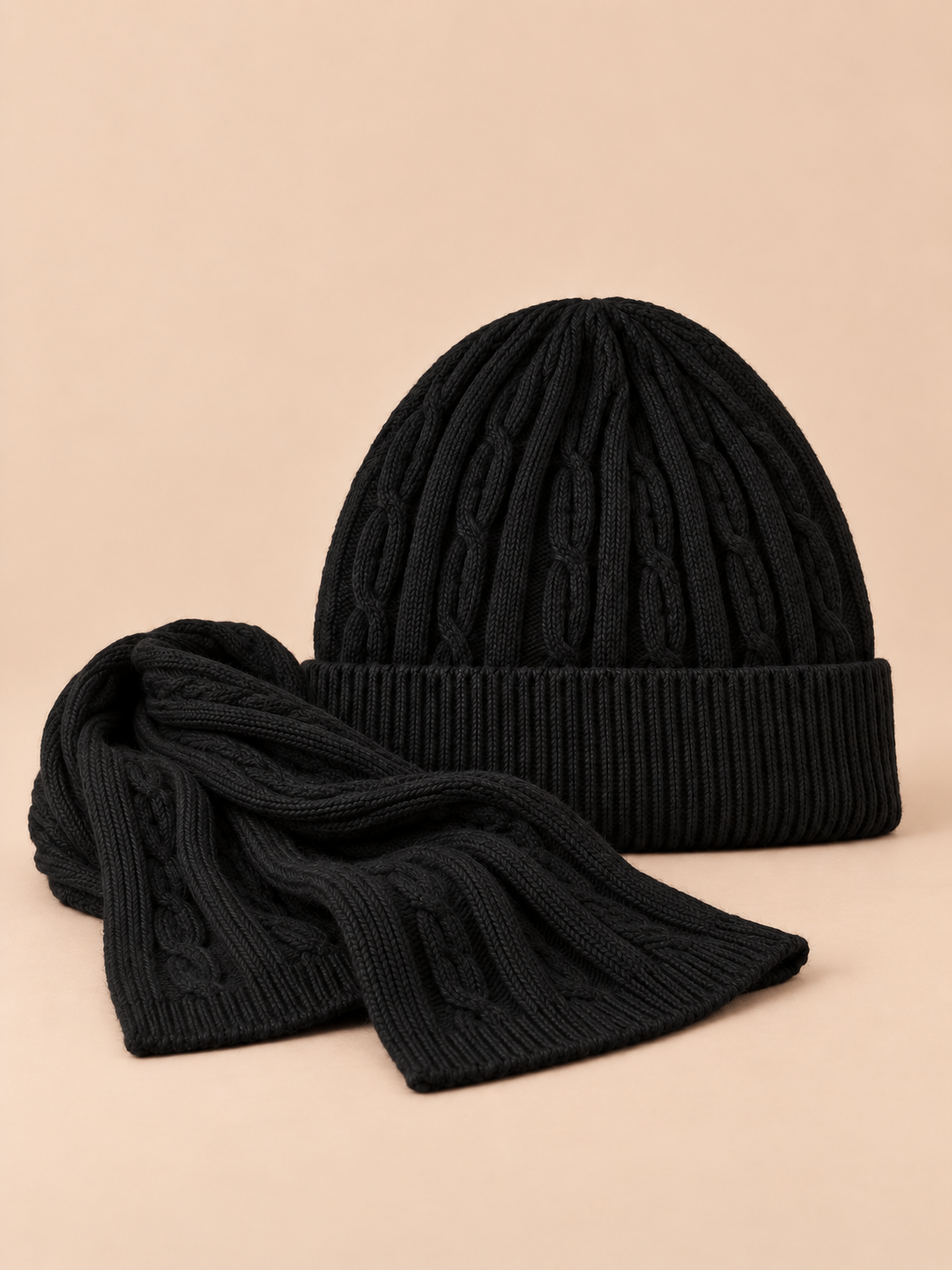 Ensemble bonnet à revers et écharpe en laine jacquard noire, vue de face sur fond pêche sable.