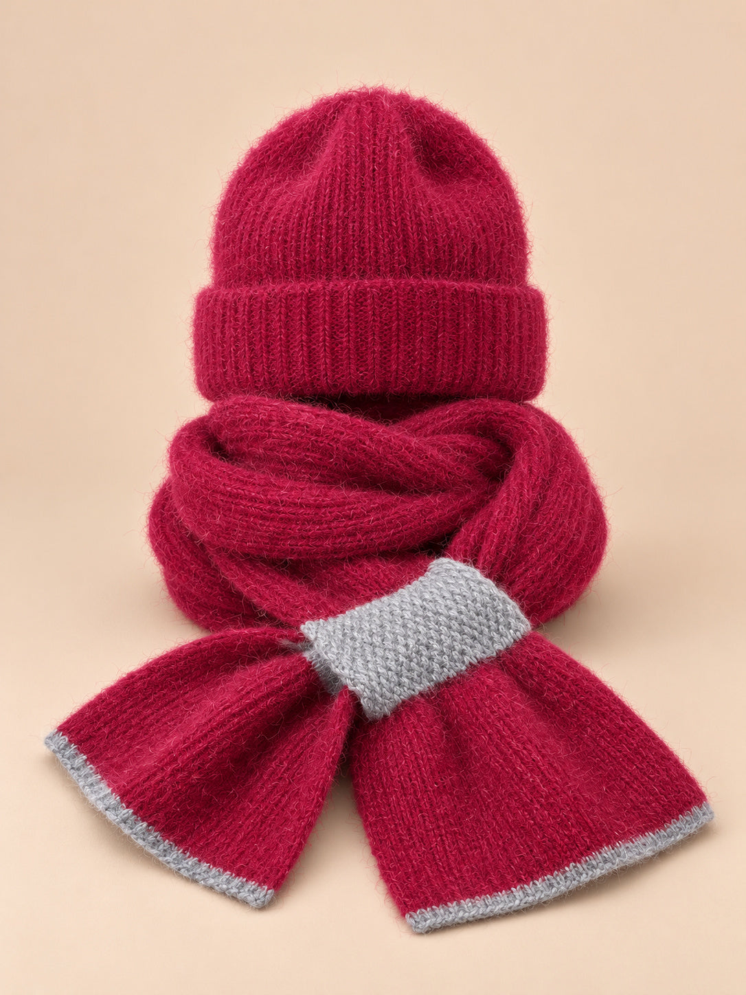 Ensemble bonnet et écharpe peluche, bordeaux, vue de face sur fond pêche sable.
