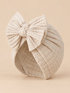 Baby-Turbanmütze für Mädchen aus Baumwollstrick mit Knoten – Farbvariante Beige, Dreiviertelansicht